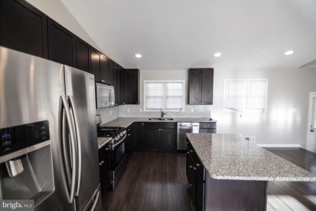 3323 Southgreen Road Baltimore, MD 21244 - Photo 4 of 25 a kitchen with granite countertop a refrigerator a sink a stove and wooden cabinets