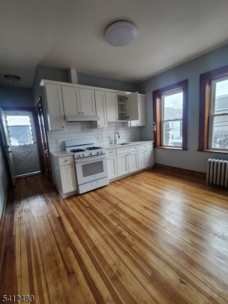 a large kitchen with cabinets wooden floor and stainless steel appliances