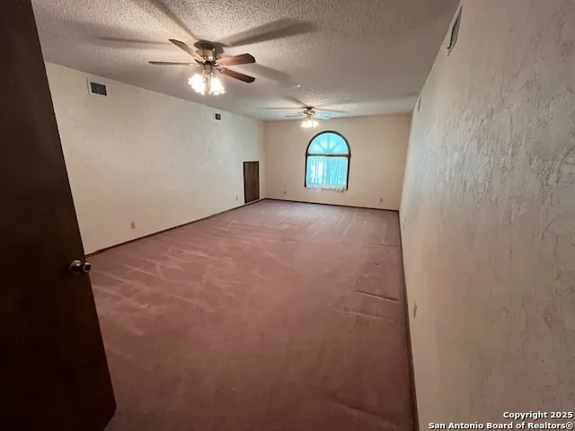 an empty room with ceiling fan and window