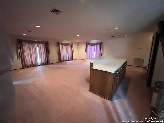 a view of an empty room with kitchen and a window