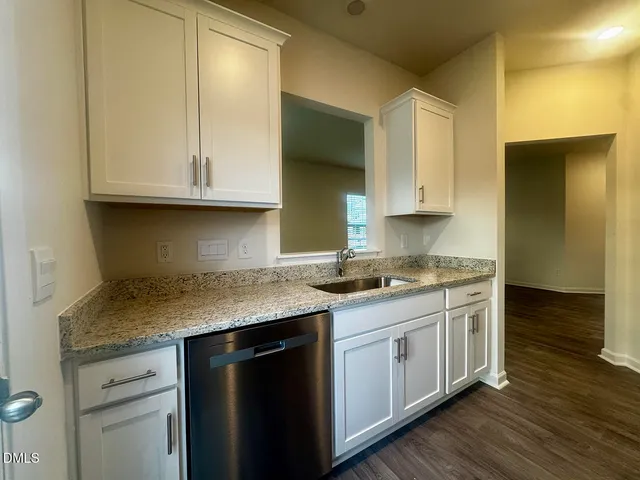 a kitchen with granite countertop white cabinets and a sink