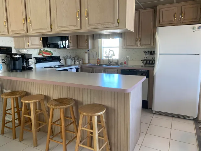 a kitchen with stainless steel appliances granite countertop a refrigerator a sink a stove and white cabinets