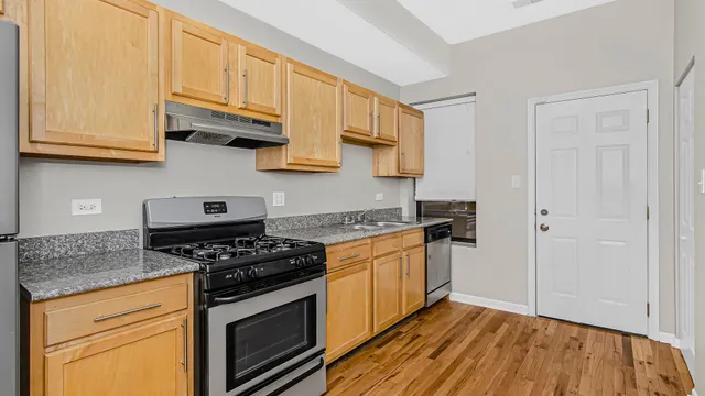 a kitchen with stainless steel appliances granite countertop a stove and a white cabinets