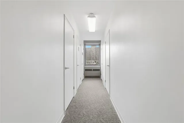 a view of a hallway with wooden floor and a bathroom