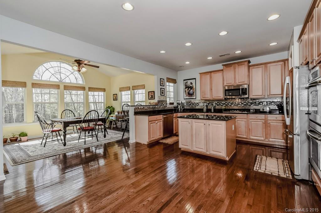 315 Calming Way Tega Cay, SC 29708 - Photo 8 of 24 a kitchen with stainless steel appliances granite countertop wooden floors and white cabinets