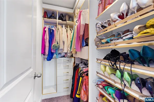 a view of walk in closet with clothes and shoes