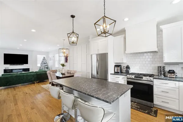 a kitchen with a stove a kitchen island a sink dishwasher a dining table and chairs with wooden floor