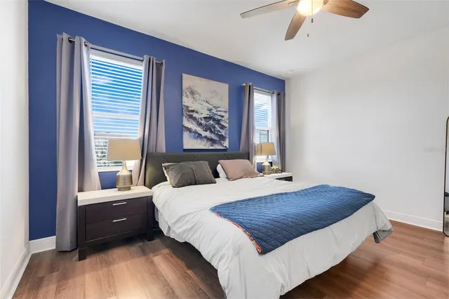 a bedroom with a bed and a large mirror with wooden floor