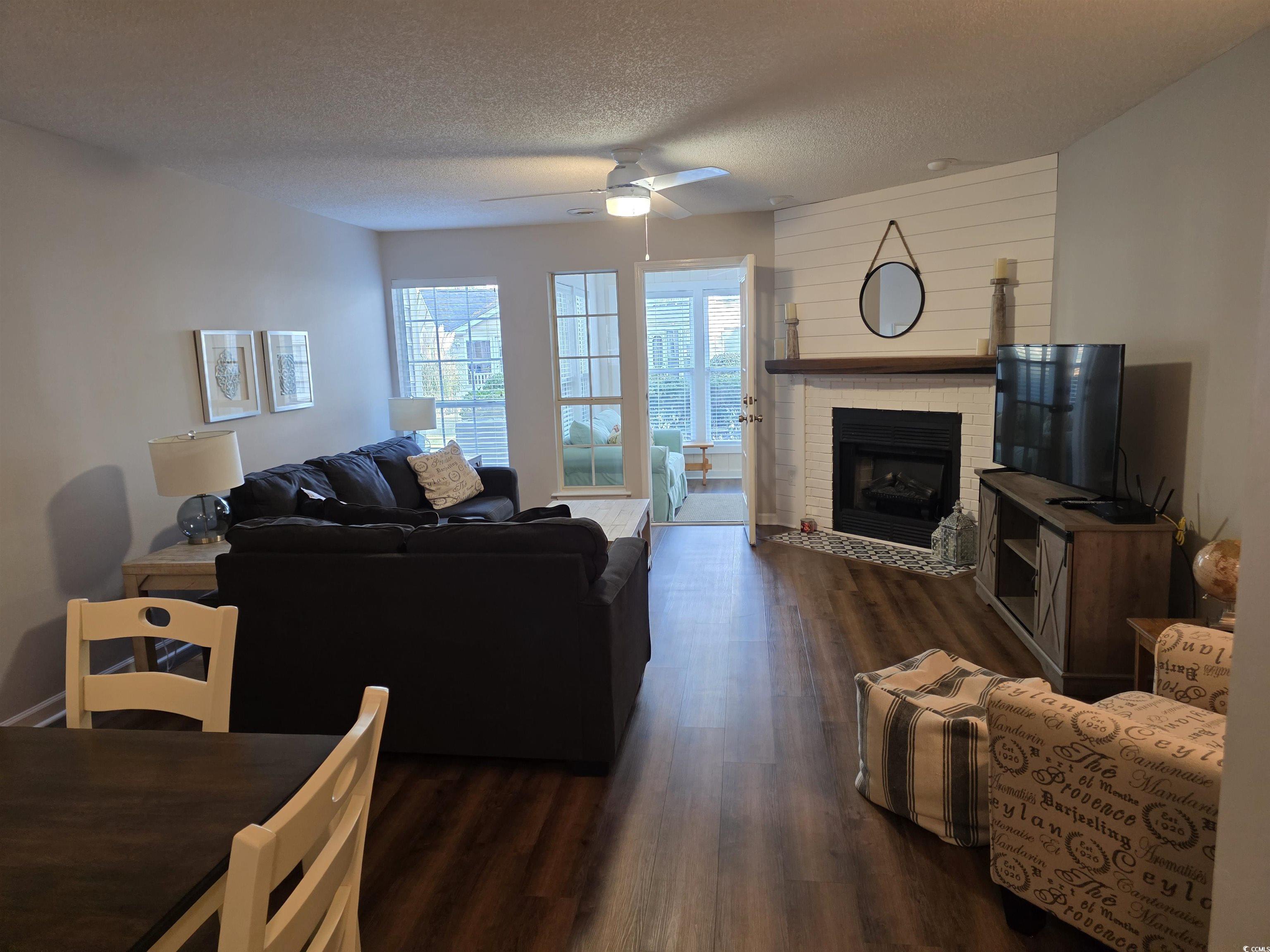 1637 Club Circle, Unit 18 Pawleys Island, SC 29585 - Photo 3 of 20 Living area featuring dark wood-style flooring, a fireplace, a textured ceiling, and ceiling fan