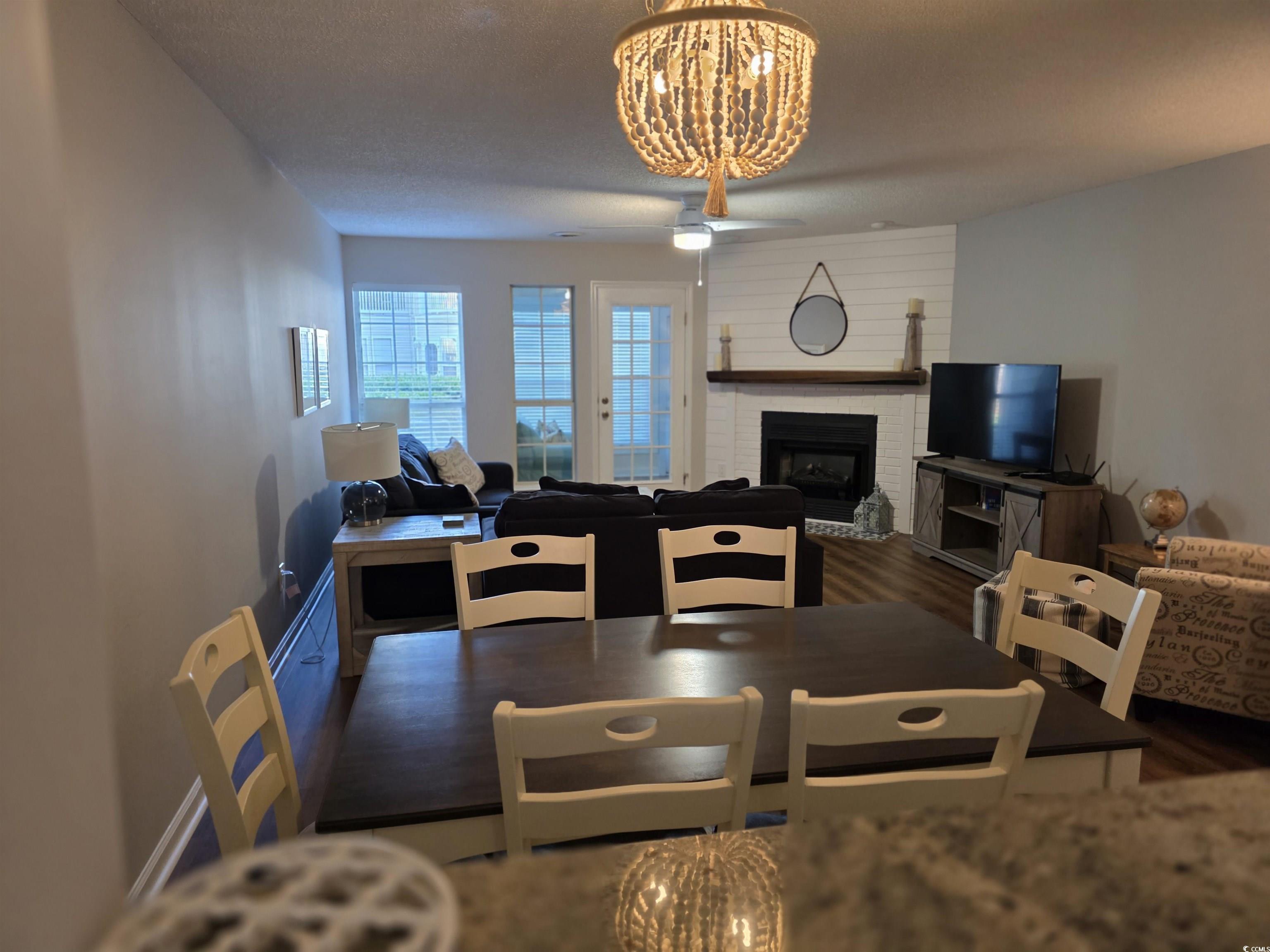 1637 Club Circle, Unit 18 Pawleys Island, SC 29585 - Photo 4 of 20 Dining room featuring a fireplace, dark wood-style floors, and a chandelier
