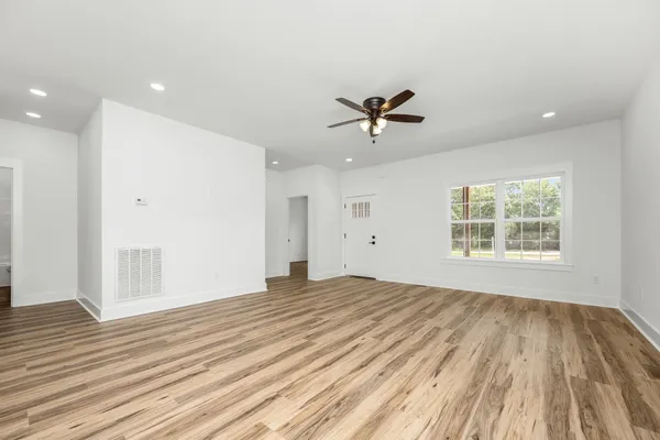 a view of an empty room with wooden floor and a window
