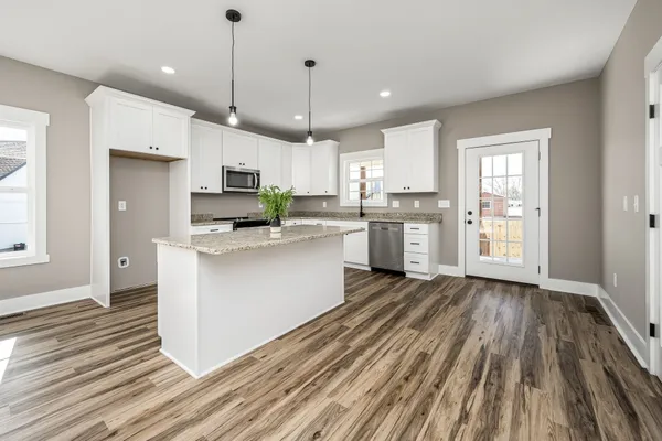 a large kitchen with cabinets wooden floor stainless steel appliances and window