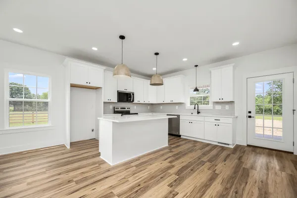a kitchen with white cabinets and wooden floor