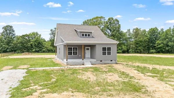 a view of a house with a yard and a large tree