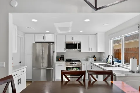 a kitchen with a refrigerator a microwave and white cabinets