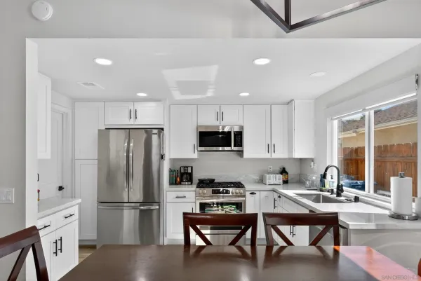 a kitchen with a refrigerator a microwave and white cabinets
