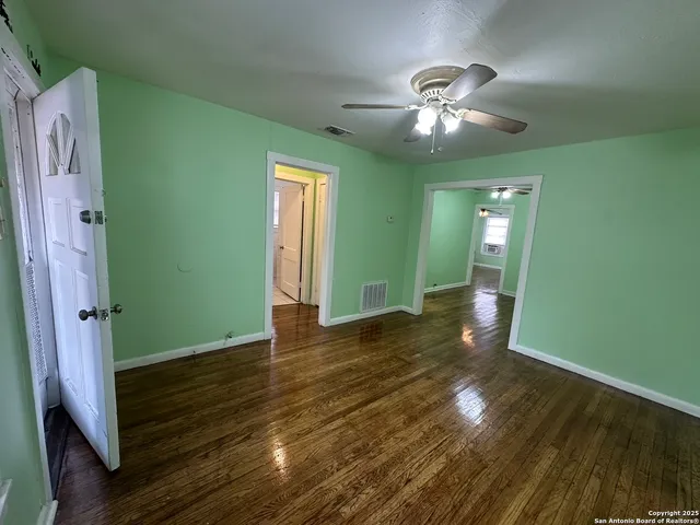 a view of an empty room with wooden floor and a window