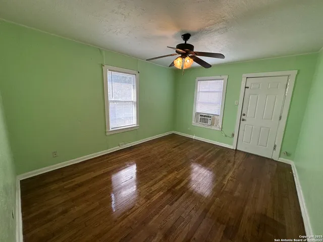 a view of an empty room with window and wooden floor