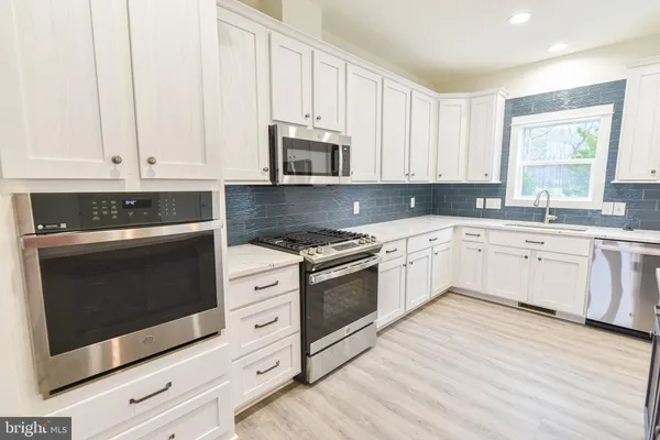 a white kitchen with granite top and stainless steel appliances