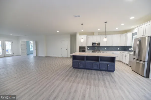 a large kitchen with stainless steel appliances kitchen island a large counter top and wooden floors