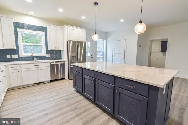 a large kitchen with kitchen island a stove a sink a center island and wooden cabinets
