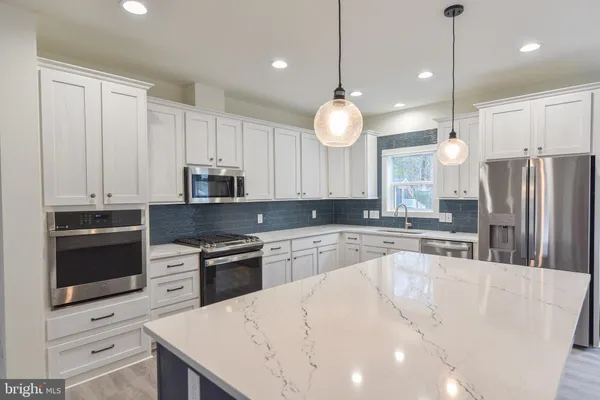 a kitchen with stainless steel appliances granite countertop a sink a stove a refrigerator and island with wooden floor