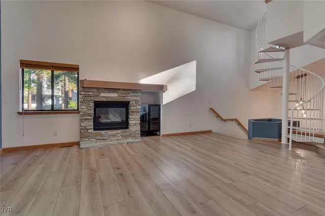 an empty room with wooden floor fireplace and windows