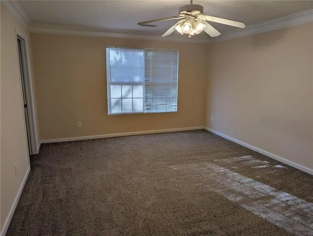 an empty room with a chandelier fan and windows