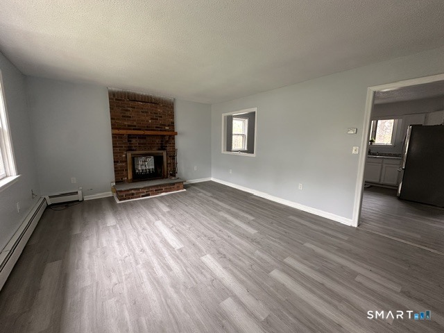 259 Westchester Road, Unit A Colchester, CT 06415 - Photo 8 of 22 an empty room with wooden floor fireplace and windows