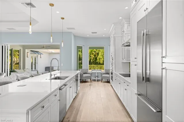 a large white kitchen with a large window and stainless steel appliances