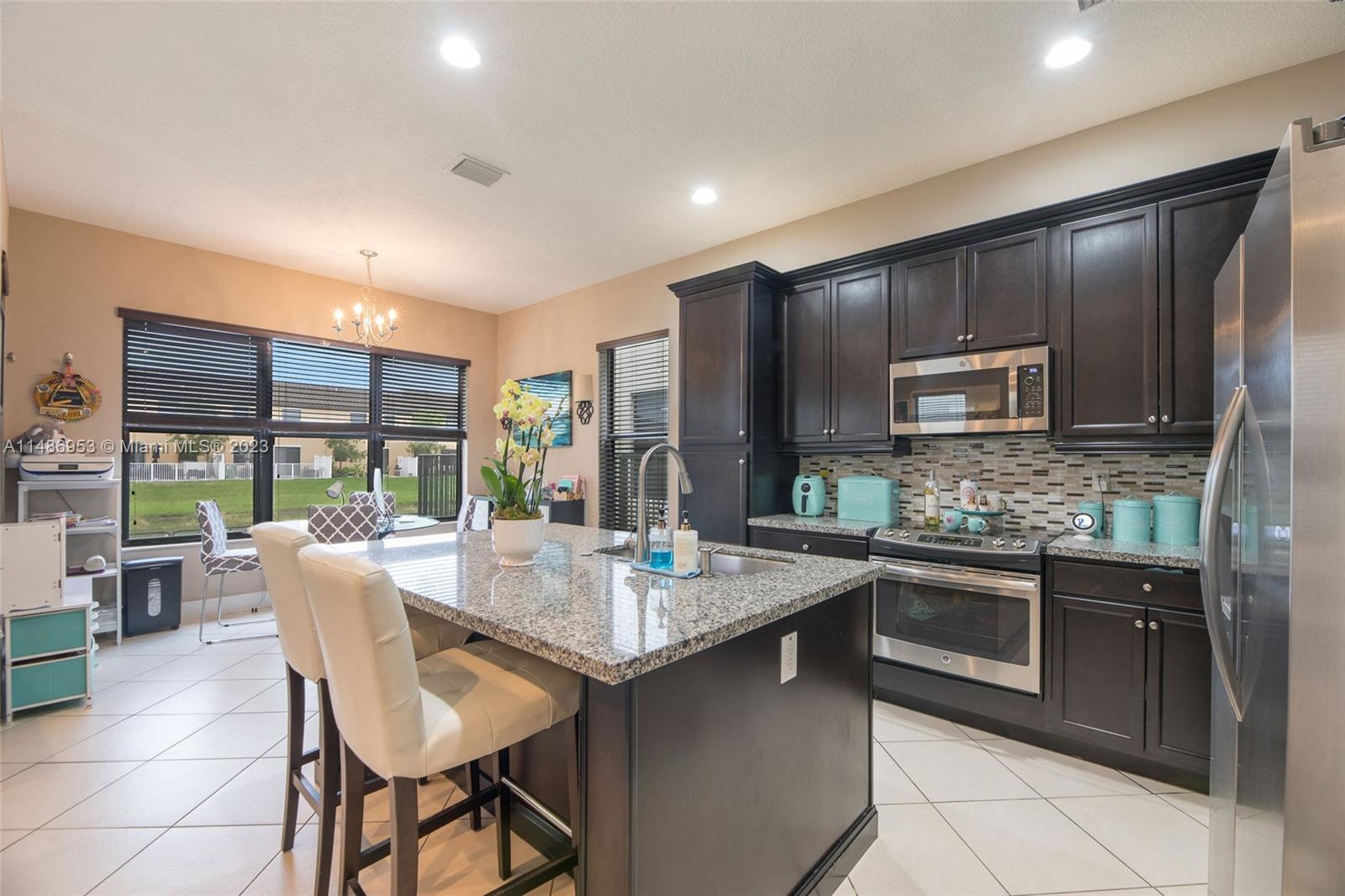 3308 West 95th Terrace Hialeah, FL 33018 - Photo 10 of 43 a kitchen with stainless steel appliances granite countertop a stove top oven a sink dishwasher a dining table and chairs with wooden floor