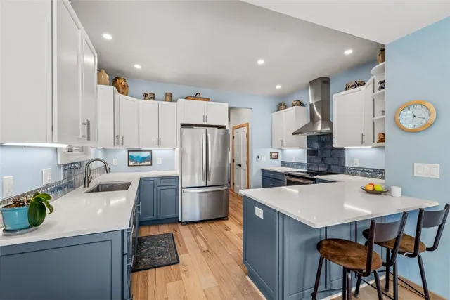 a kitchen with stainless steel appliances a sink a stove a refrigerator cabinets and dining table