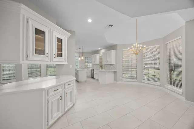 a large white kitchen with granite countertop a large window and white cabinets