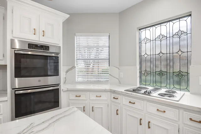 a kitchen with granite countertop cabinets stainless steel appliances and a large window
