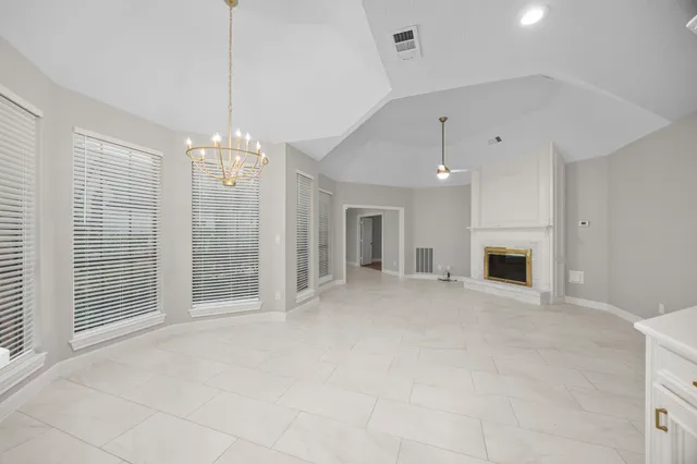 a view of an empty room with chandelier and fireplace