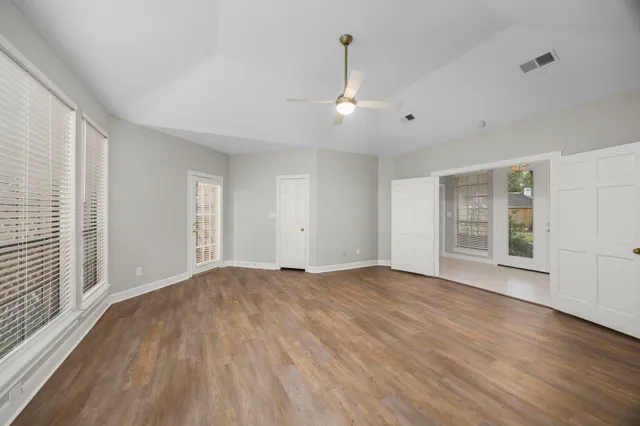 a view of an empty room with wooden floor and a window