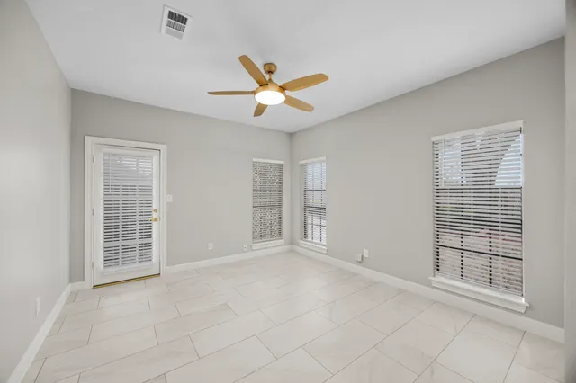 an empty room with windows and ceiling fan