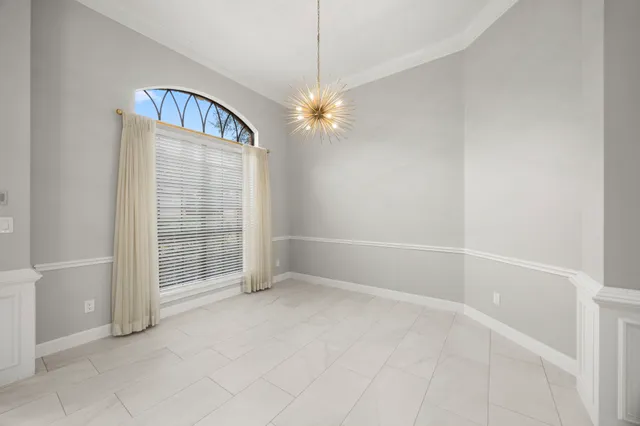 an empty room with chandelier fan and windows