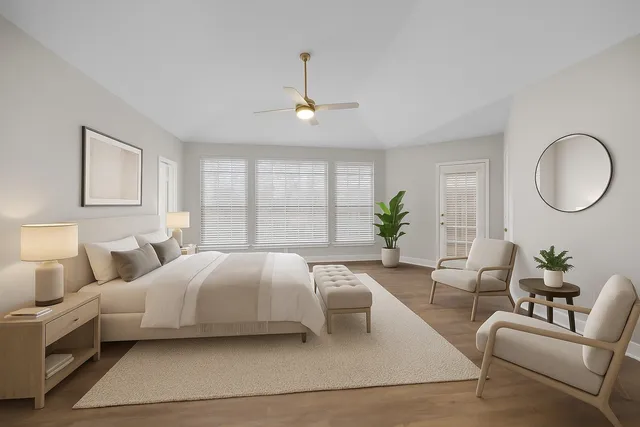 a bedroom with a large bed couch and windows