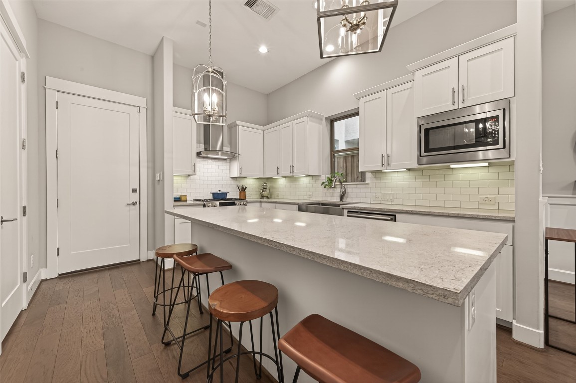 604 West Pierce Street Houston, TX 77019 - Photo 11 of 33 a kitchen with stainless steel appliances granite countertop a sink a stove a microwave oven a refrigerator with white cabinets and wooden floor
