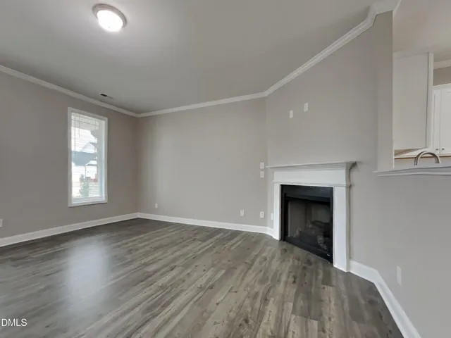 an empty room with wooden floor a fireplace and windows
