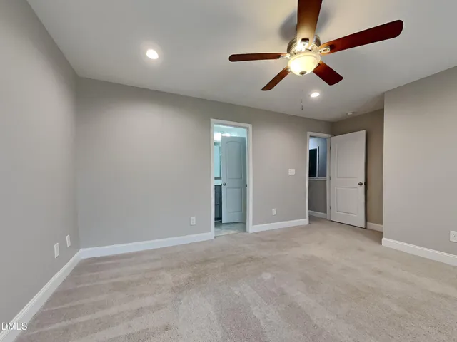 an empty room with chandelier fan and windows