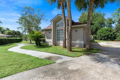 a front view of a house with a yard and palm trees