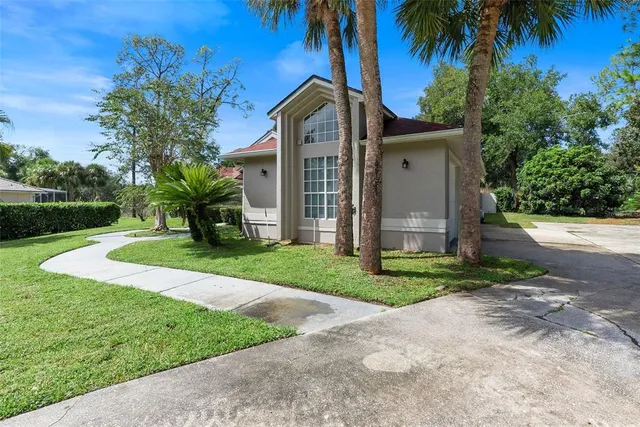 a front view of a house with a yard and palm trees