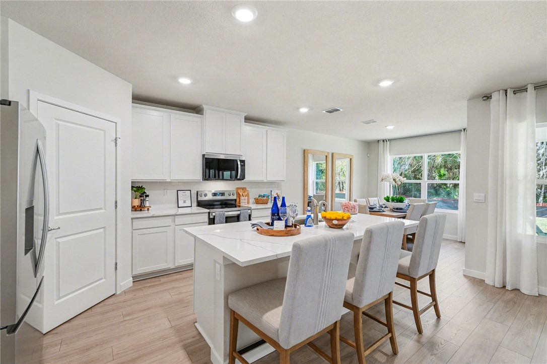 793 George Street Sebastian, FL 32958 - Photo 9 of 22 a kitchen view with stainless steel appliances granite countertop a stove a refrigerator a sink a dining table and chairs with wooden floor