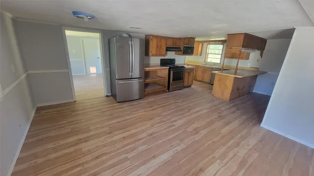 an empty room with wooden floor and a kitchen