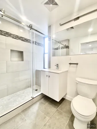 a bathroom with a sink a toilet a mirror and shower