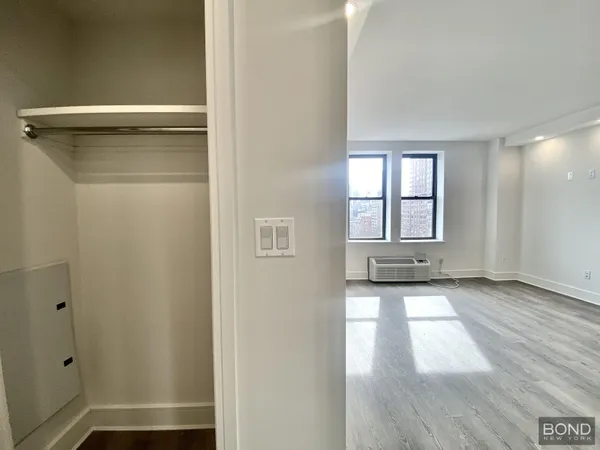 a view of a hallway with wooden floor and a cabinet