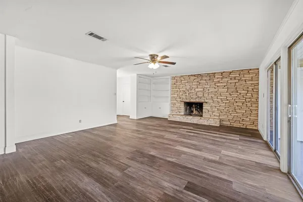 a view of an empty room with wooden floor and a fireplace