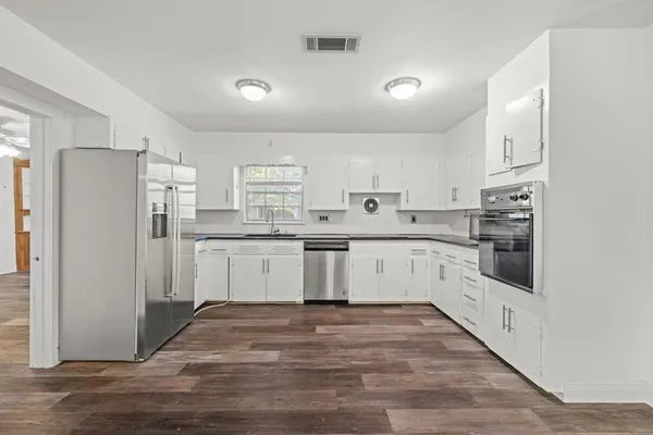 a kitchen with stainless steel appliances granite countertop a white cabinets and a refrigerator